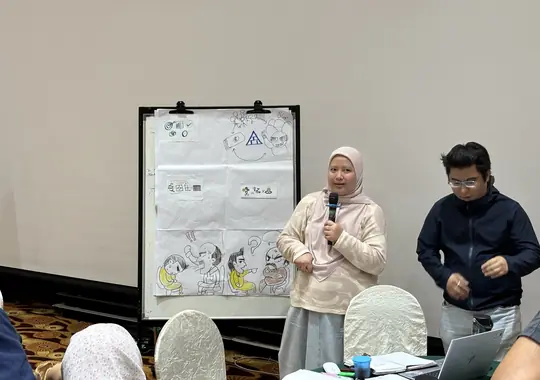 A participant presenting with a microphone beside the team's flipchart