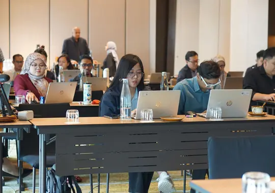 A full room of participants working on laptops in an OPI session