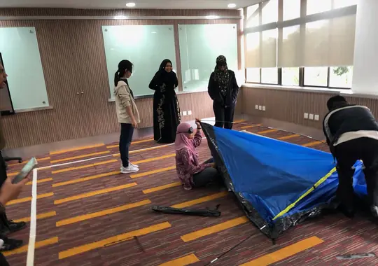 A team pitching a tent together as a teamwork exercise